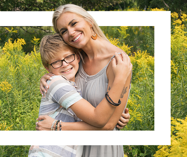 A mother and her young son hugging and smiling outdoors