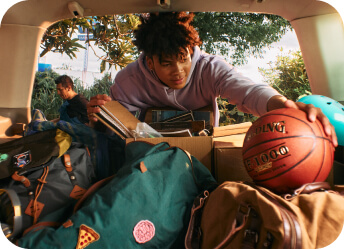 Young man grabbing basketball from car trunk